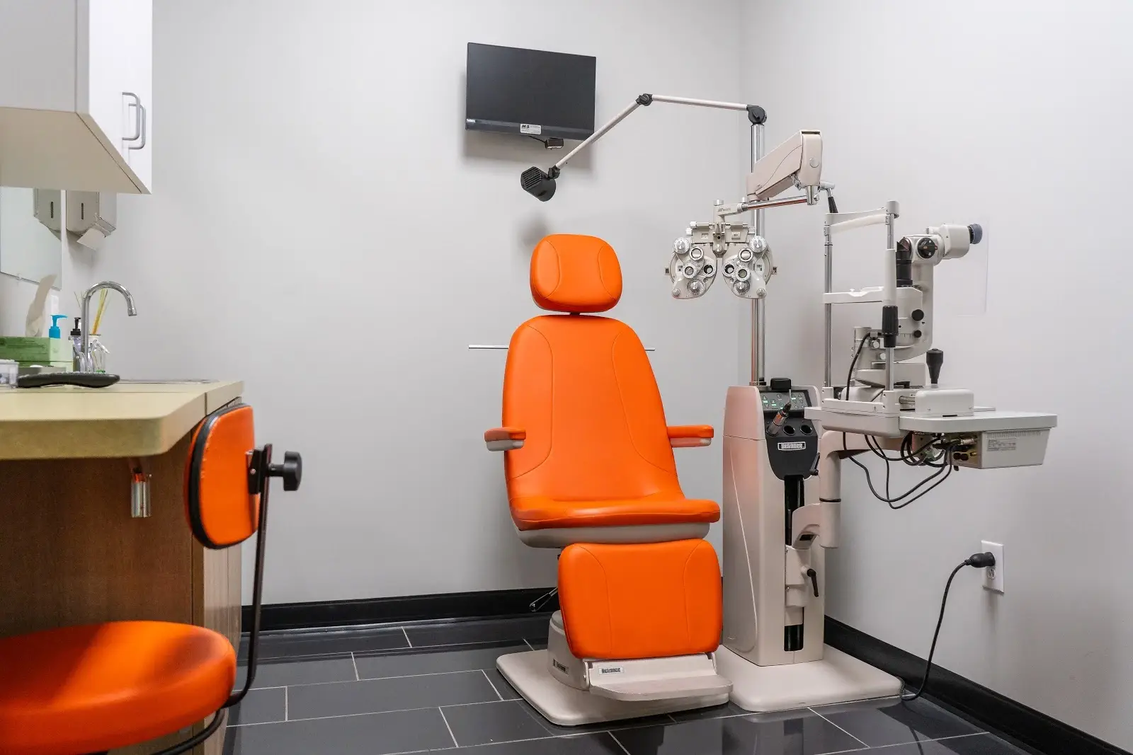 Exam room with orange chair and eye exam equipment at Omni Vision Dove Creek.