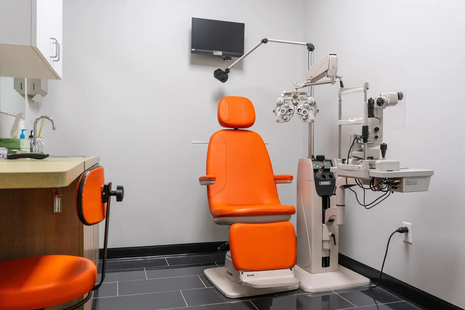 Exam room with orange chair and eye exam equipment at Omni Vision Dove Creek.