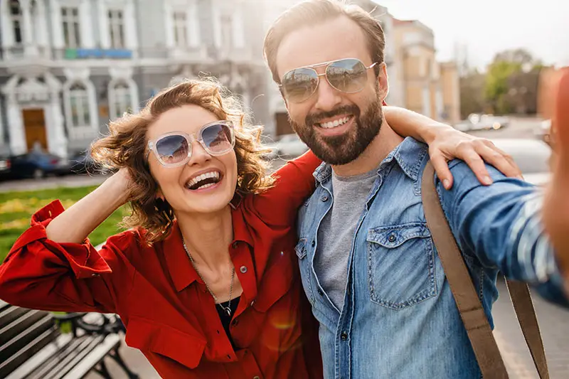 Happy female and male couple smiling with sunglasses.