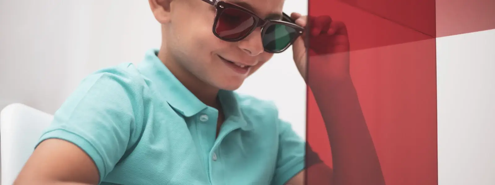 vision therapy.. A child performs a test with cards while wearing red and green glasses.