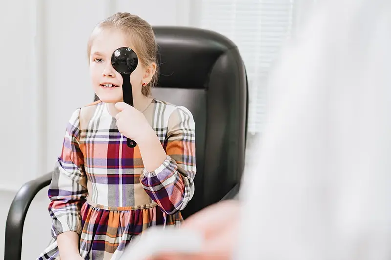 Young girl covering her eye during eye exam.