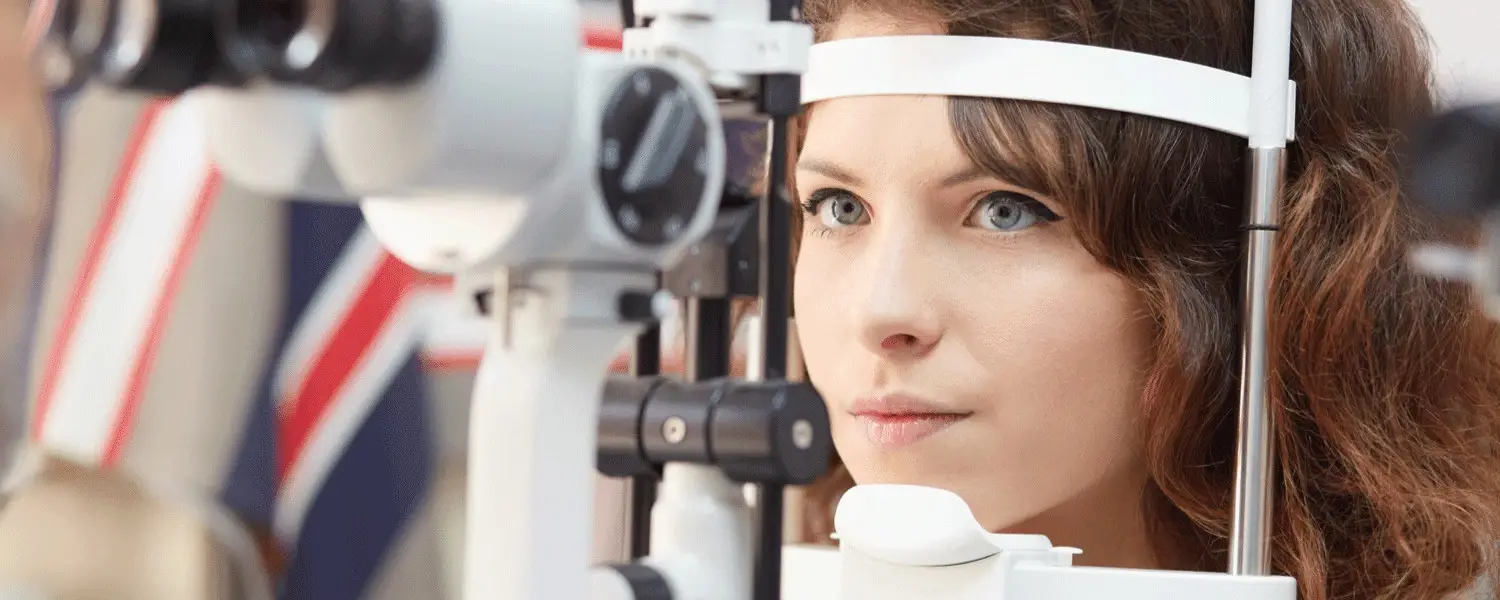 Woman looking in to a medical eye equipment during an eye exam.
