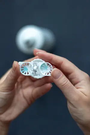 A person holding a white contact lens in their hand.