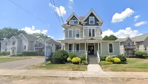 A house on a street corner with a sign and walkway