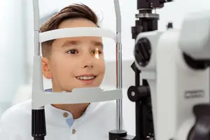 A young boy is getting his eyes checked by a doctor using a machine.