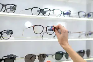A person is examining a pair of glasses in a display case.