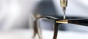 A closeup of a pair of glasses being adjusted with a tool