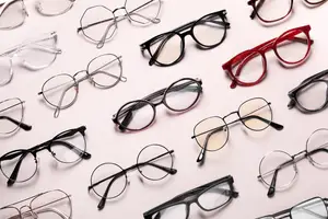 Collection of various eyeglasses displayed on a pink surface