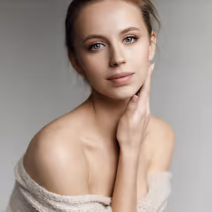 Woman posing for a portrait with a light background and a knitted shawl around her shoulders