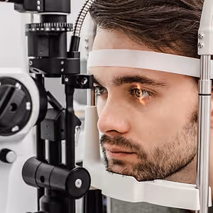 A man having his eyes checked with a slit lamp in an optometrist's office.