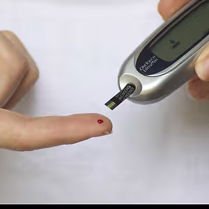 A close up of a person using a OneTouch UltraMini blood glucose meter.