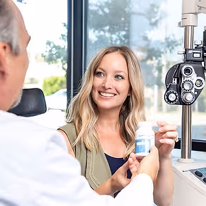Woman in a medical office with a doctor holding a bottle of vitamins