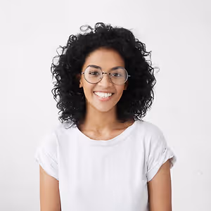 Portrait of a smiling woman with curly hair wearing a white shirt and glasses