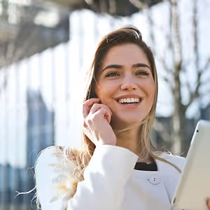 A smiling woman holding a tablet and talking on the phone