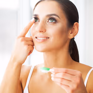 Woman inserting contact lens in eye