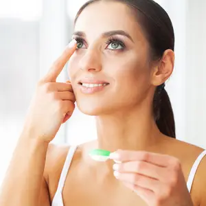 Woman inserting contact lens in eye