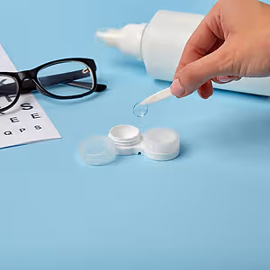 A person wearing glasses is using a white solution to clean a contact lens.