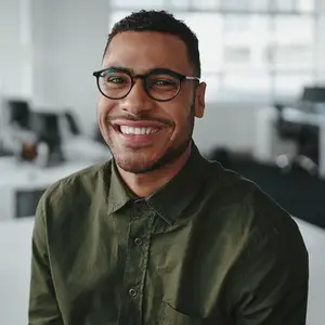 A man in a green shirt and glasses is smiling in an office setting