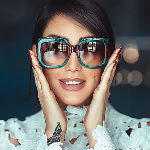 A woman wearing Gucci sunglasses and a white lace dress poses for a photo
