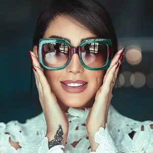 A woman wearing Gucci sunglasses and a white lace dress poses for a photo