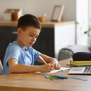 Boy sitting at a table writing on a piece of paper