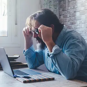 Man sitting at a desk looking stressed and frustrated.