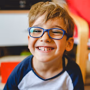 A boy wearing glasses with a smiling face