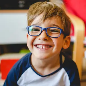 A boy wearing glasses with a smiling face