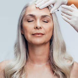 A woman with gray hair getting a facial injection in a studio