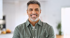 A smiling man in a kitchen wearing a green shirt