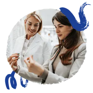 Two women, one wearing a lab coat, are examining a pair of glasses.
