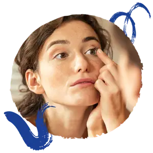 woman applying eye makeup in front of a mirror