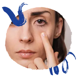 A woman is applying a cream to her eye area.