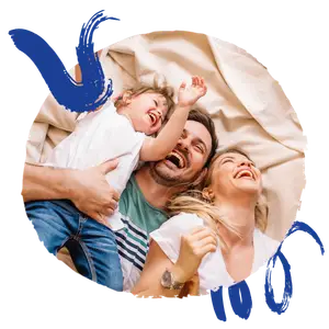 A family laying in bed together, smiling and laughing