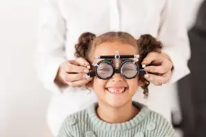 A young girl is having her eyes checked by a doctor wearing glasses.