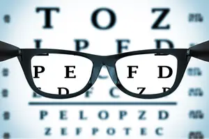 An eyeglass with lenses that show the letters PEFD and the letters on a screen with a blue background