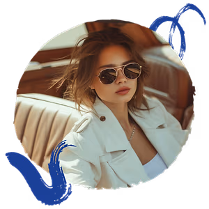 A woman wearing sunglasses, a white jacket, and a necklace sits in a car.