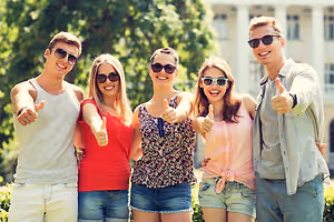 A group of five young people wearing sunglasses and smiling for a picture