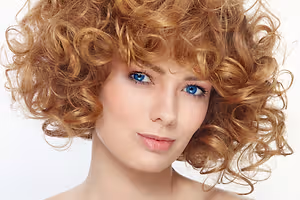 Curly-haired woman with blue eyes posing for a photo