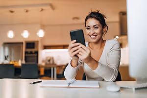 A woman taking a selfie in a kitchen with a smile on her face.