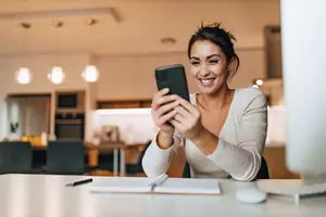 A woman taking a selfie in a kitchen with a smile on her face.