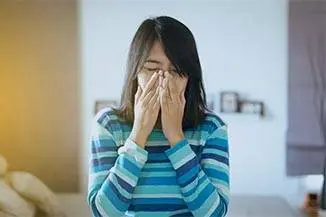 Woman with a runny nose sneezing in bed