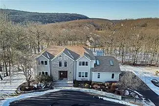 Aerial view of a large house with a driveway and trees in winter