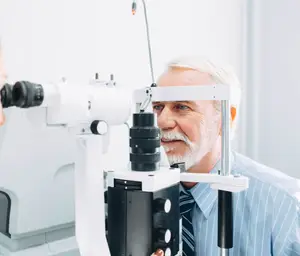 An elderly man has his eyes examined