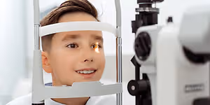 A young boy is getting his eyes examined by an optometrist.
