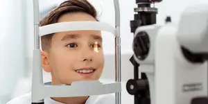 A young boy is getting his eyes examined by an optometrist.
