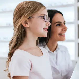 A girl wearing glasses and a woman standing behind her smiling