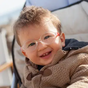A baby with glasses and a brown coat smiles
