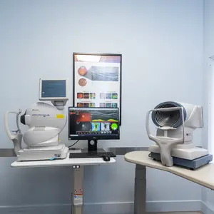 A eye exam office with an eye examination machine and computer monitor on a table