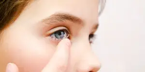 A girl about to insert a contact lens into her eye